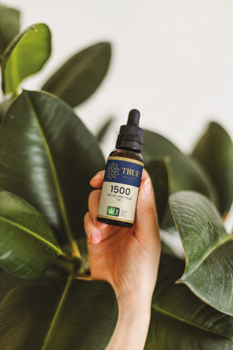 Hand holding a True Wellness oil