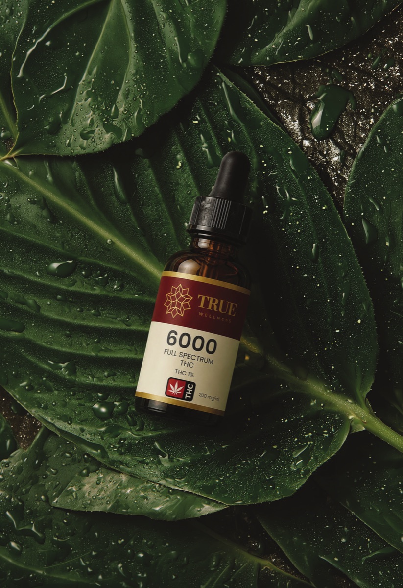 True Wellness oil on green leaves